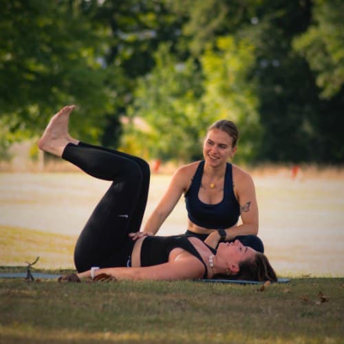 Eva accompagne une élève pendant une séance de Pilates en plein air